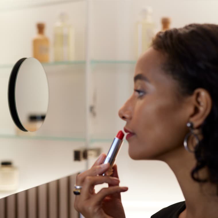 Femeie care aplică machiaj în oglindă Femeie care aplică machiaj în oglindă